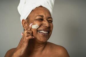 Happy African senior woman having skin care spa day - People wellness lifestyle concept photo