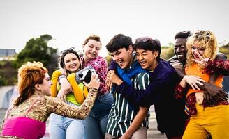 Happy young diverse friends having fun with old vintage video camera outdoor - Youth people millennial generation concept photo