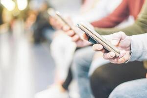 Group of millennial friends watching their smart mobile phones - New generation addicted to new technology trends - Concept of people, tech and social media network photo