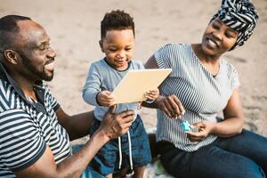 Happy African family having fun on the beach during summer holidays - Parents love concept photo