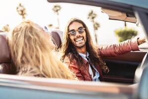 Happy young couple doing road trip in tropical city - Travel people having fun driving in convertible car discovering new places - Relationship and youth vacation lifestyle concept photo