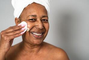 Happy African senior woman having skin care spa day - People wellness lifestyle concept photo