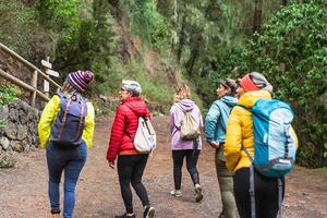 Group of women with different ages and ethnicities having fun walking in the woods - Adventure and travel people concept photo