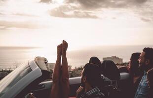 contento amigos conducción en convertible coche a puesta de sol - joven personas teniendo divertido durante vacaciones la carretera viaje en cabriolé - amistad, viaje y juventud estilo de vida concepto foto