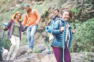 Group of friends with backpacks doing trekking excursion on mountain - Young  tourists walking and exploring the nature - Trekker, hike and travel people concept photo