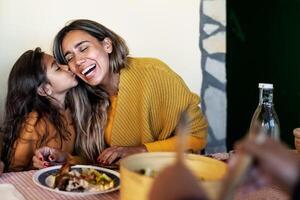 contento Hispano madre teniendo oferta momento con hija mientras comida juntos con familia - padres amor concepto foto