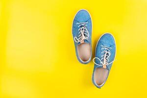 Blue shoes stand on an isolated yellow background photo