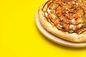 Delicious large pizza with bacon and spinach on a yellow background photo