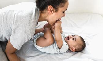 Happy mother playing with her baby lying together on bed photo