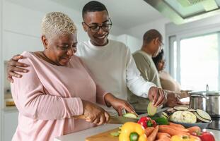 contento africano familia teniendo divertido en moderno cocina preparando comida receta con Fresco vegetales - comida y padres unidad concepto foto