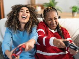 Happy African mother and daughter having fun playing online video games at home - Gaming entertainment and technology concept photo