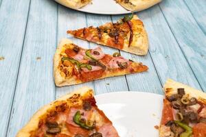 Two different delicious big pizzas on a blue wooden background photo