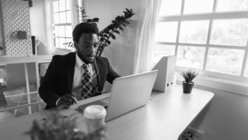 Business African man doing online video conference on laptop inside modern office - Black and white editing photo