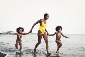 Happy African family on the beach during summer holidays - Afro American people having fun on vacation time - Parents love and travel lifestyle concept photo