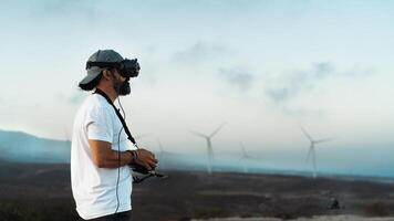 Drone engineer using first person view technology on the turbine farm - Alternative energy and aerial engineering concept photo