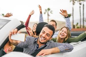 contento amigos tomando selfie y grabación con móvil inteligente teléfono en convertible coche - joven personas teniendo divertido en cabriolé auto durante su la carretera viaje vacaciones - viaje y juventud estilo de vida concepto foto