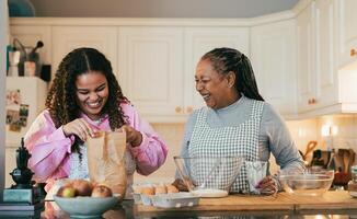 Happy African mother and daughter preparing a homemade dessert photo