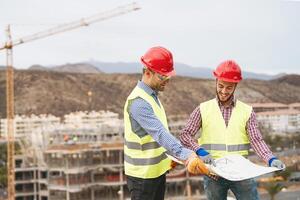 Work engineers discussing about new building area - Young builders reading the project in the construction site - Carpentry teamwork engineering concept photo