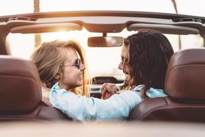 Happy young couple doing road trip in tropical city - Travel people having tender moments in trendy convertible car while discovering new places - Relationship and youth vacation lifestyle concept photo