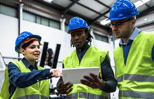 equipo de ingenieros trabajando en robótico fábrica mientras analizando el proyecto en el tableta - tecnología industria concepto foto