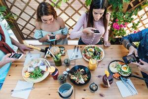 joven personas tomando comida imágenes con móvil teléfono inteligente a compartir en social medios de comunicación mientras teniendo sano comida en bar restaurante - juventud Generacion z y tecnología concepto foto