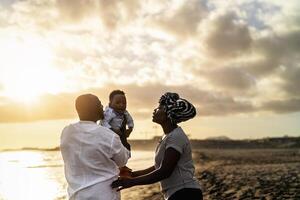 contento africano familia teniendo divertido en el playa durante verano vacaciones - padres amor y unidad concepto foto