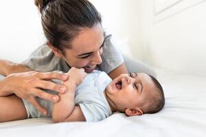 Happy mother playing with her baby lying together on bed photo