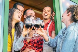 contento amigos aplausos con lentes de rojo vino en terraza - joven personas teniendo divertido Bebiendo, tostado y riendo juntos en un viñedo casa - amistad y juventud estilo de vida concepto foto