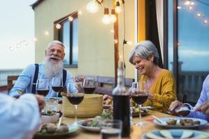 Happy senior friends having fun dining together on house patio - Elderly lifestyle people and food concept photo