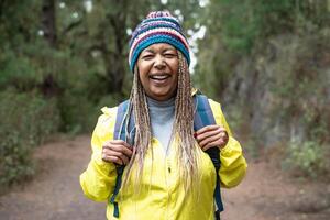 Happy Afro senior woman having a walk in the woods - Adventure and travel people concept photo