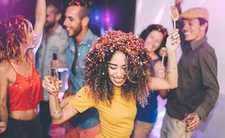 Happy friends doing party drinking champagne in nightclub - Group young people having fun celebrating new year holidays together in disco club - Youth entertainment lifestyle concept photo