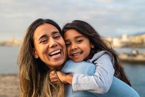 contento latín madre disfrutando hora con su niño en el playa - familia y amor concepto foto