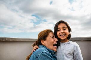 Happy Hispanic child enjoying time with grandmother at house rooftop photo