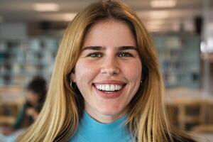 Happy young girl smiling into the camera while standing inside university library photo