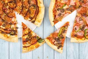 Two different delicious big pizzas on a blue wooden background photo