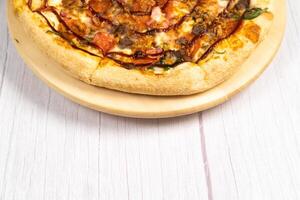 delicioso grande Pizza con tocino y Espinacas en un ligero de madera antecedentes foto