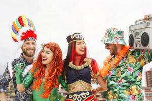 Happy friends celebrating carnival party outdoor - Young crazy people having fun wearing costumes listening music with vintage boombox stereo - Youth holidays culture lifestyle concept photo