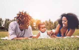 Happy African family enjoying together a weekend sunny day outdoor - Mother and father having fun with their daughter in a public park - Love, parents and happiness concept photo