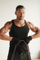 A man in black sportswear is engaged in strength fitness using a rubber loop indoors photo