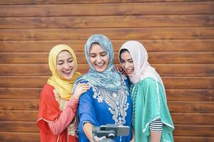 Happy muslim women making video with gimbal smart phone camera in college - Arabian young people having fun with new technology for social media - Millennials, generation z and religion concept photo