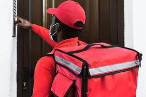 African rider man delivering meal to customers home while wearing face mask during corona virus outbreak - Delivery food concept photo