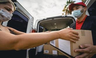 Delivery man wearing face protective mask to avoid corona virus spread - Young express courier delivering to costumer during coronavirus outbreak - Deliver and online buying concept photo