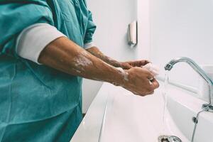 Surgeon washing hands before operating patient in hospital - Medical worker getting ready for fighting against corona virus pandemic - Health care and hygiene concept photo