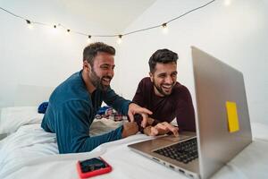 Happy gay men couple using laptop in bed - Homosexual love and gender equality in relationship concept photo
