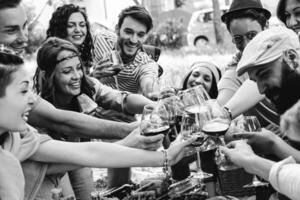 grupo de personas aplausos con rojo lentes de vino - contento joven amigos disfrutando picnic en un parque con comida mi bebida - negro y blanco editar - juventud concepto - atención en mujer con banda en el izquierda foto