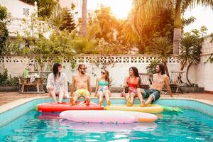grupo de contento amigos relajante en nadando piscina - joven personas teniendo divertido en exclusivo verano tropical vacaciones - amistad, Días festivos y juventud estilo de vida concepto foto