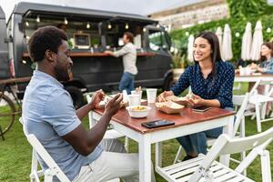 contento multirracial amigos teniendo divertido comiendo en un calle comida camión mercado foto