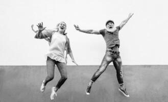 Happy crazy senior couple jumping together outdoor - Mature trendy people having fun celebrating and dancing outside - Concept of happiness, retired freedom, carefree, love and relationship photo