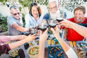 contento mayor amigos tostado con rojo vino lentes a cena hora al aire libre - maduro personas teniendo divertido comida juntos fuera de - mayor estilo de vida, comida y beber, retirado y pensionistas concepto foto