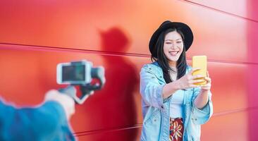 Asian fashion woman vlogging and using mobile smart phone outdoor - Happy Chinese trendy girl having fun making video with gimbal camera - Millennials people, Generation z and technology concept photo